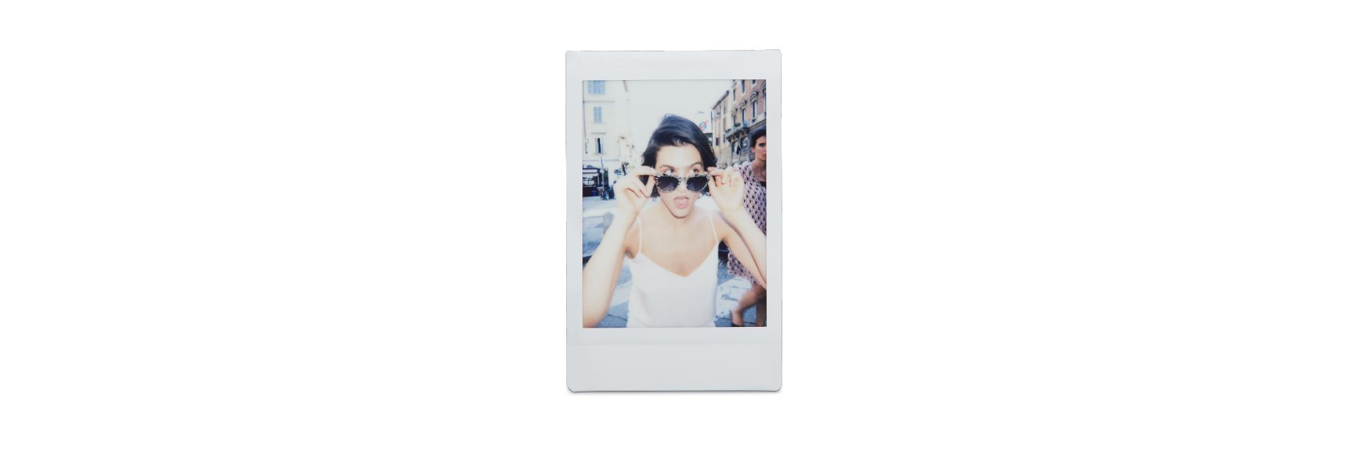 Polaroidfoto einer Frau mit Sonnenbrille, die überrascht in die Kamera schaut.