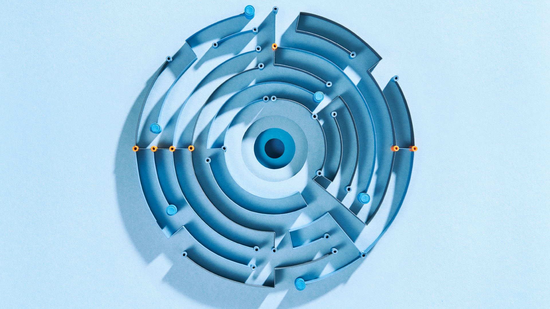 Kreisförmiges, abstraktes Labyrinth aus Papier mit orangenen Highlights auf hellblauem Hintergrund.