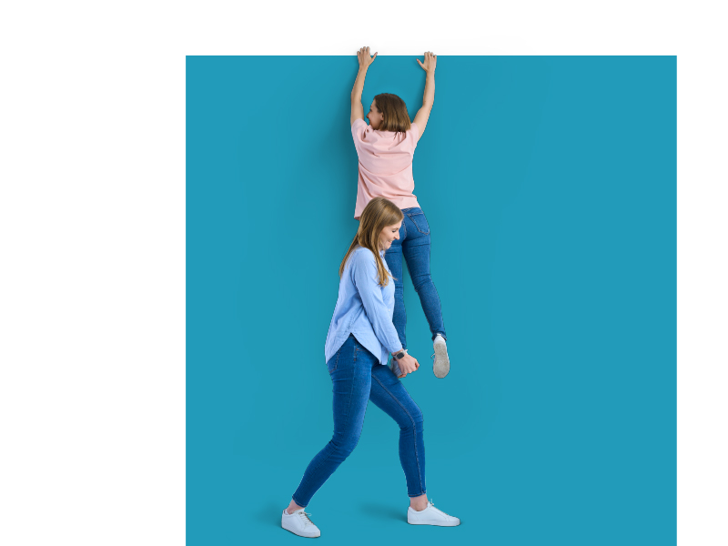 Zwei Personen machen Räuberleiter vor blauem Hintergrund.